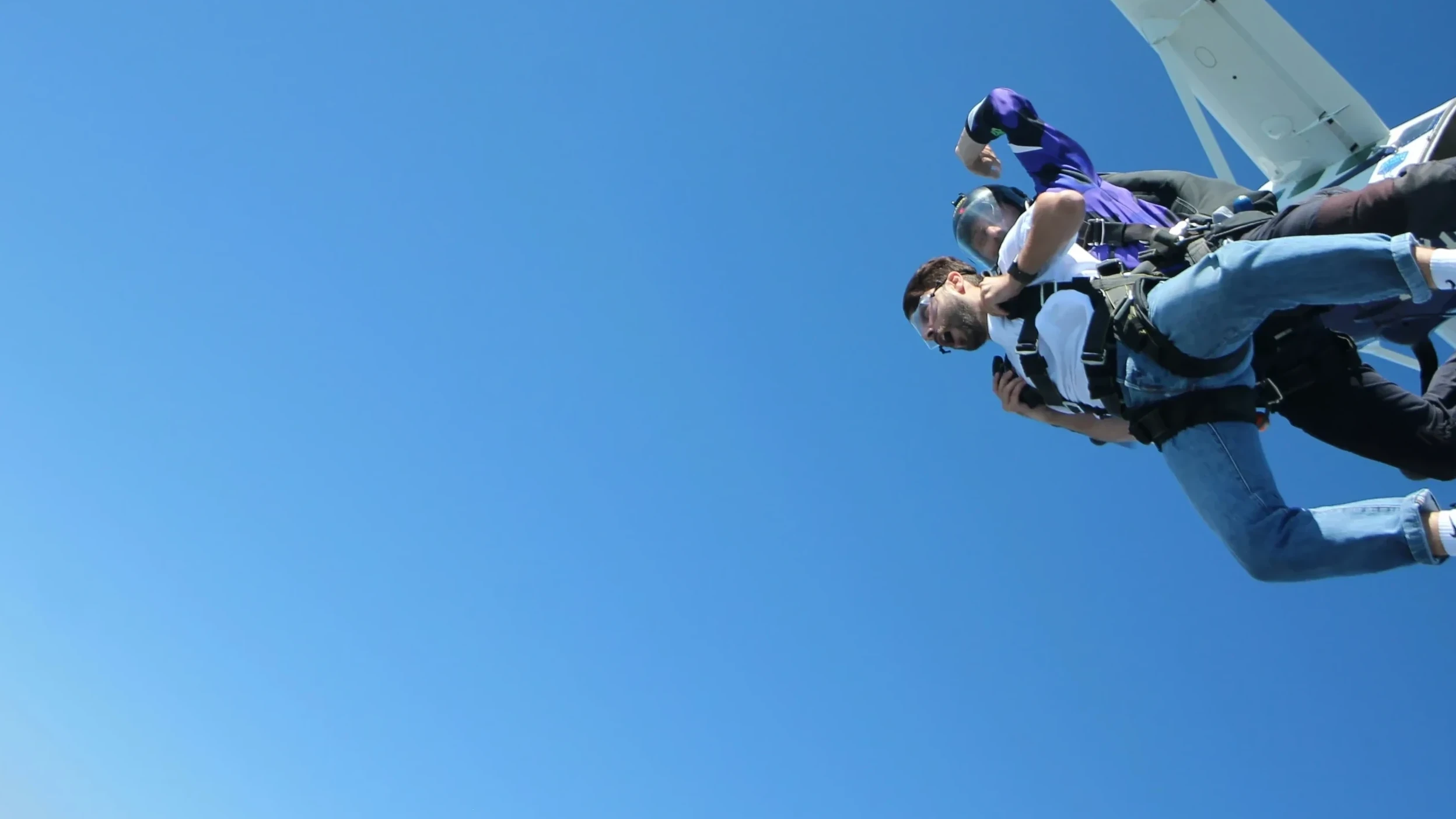 People enjoying a tandem skydive experience above a scenic coastline